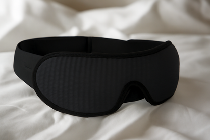 Blackout sleep mask on white bedding, Sleep Oasis New Year gift for better rest