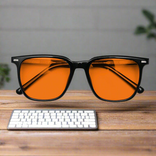Sunglasses with orange lenses and black frames on a light gray background