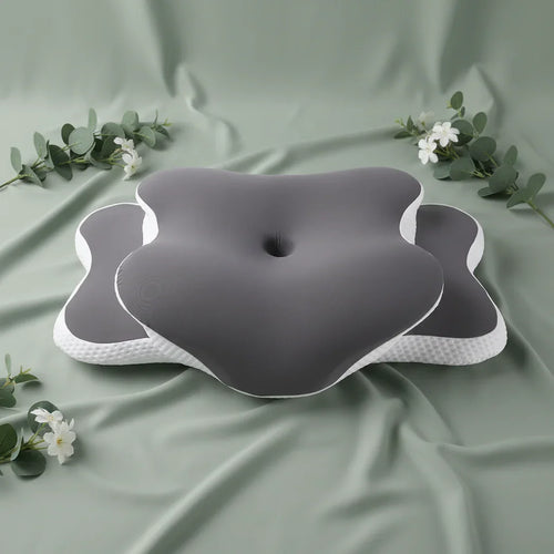 Orthopedic cervical pillow with ergonomic shape on sage green spa-inspired background with eucalyptus and white flowers.