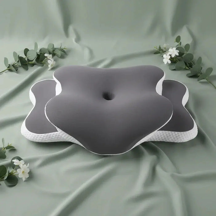 Orthopedic cervical pillow with ergonomic shape on sage green spa-inspired background with eucalyptus and white flowers.